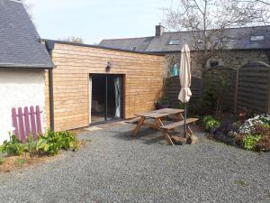 una mesa de picnic y una sombrilla junto a un edificio en Breton stone house in Saint Gilles les Bois, en Saint-Gilles-les-Bois