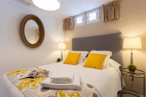 una camera da letto con letto, cuscini gialli e specchio di Genteel Home Tetuan Marbella a Marbella