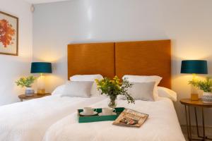 Una cama con un jarrón de flores y libros encima. en Genteel Home Tetuan Marbella, en Marbella