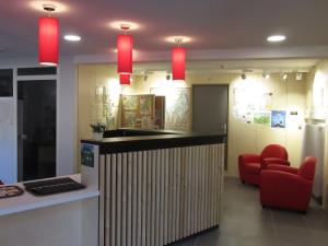 a lobby with a bar with red chairs and lights at Village vacances de Marc in Auzat