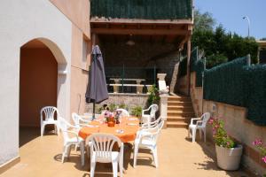 um pátio com uma mesa, cadeiras brancas e um guarda-sol em Villa Costa. em Tossa de Mar