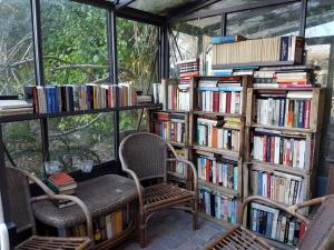 een kamer met 2 stoelen en boekenplanken gevuld met boeken bij Camomilla in Ravenna