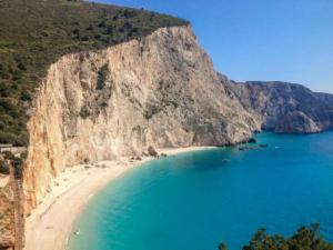 a beach with blue water and a large cliff at Karya House in Kariá