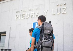a man with a backpack and a woman with a backpack standing in front of at Hotel Rural Piedra Y Luz in Hinojosa del Duque