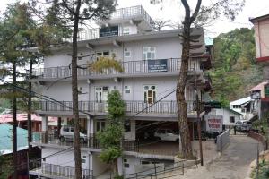 a white building with balconies on the side of it at THE HIMALAYAS GUEST HOUSE in Dharamshala