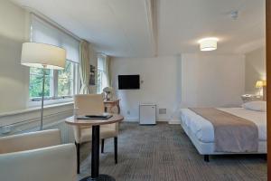 ein Hotelzimmer mit einem Bett, einem Tisch und einem Stuhl in der Unterkunft Hotel Randduin in Oostkapelle