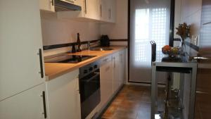 a kitchen with white cabinets and a sink and a stove at Cabárceno in La Penilla