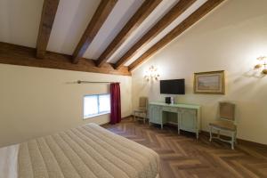 a bedroom with a bed and a desk with a television at Grand Hotel Liberty in Riva del Garda