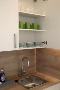 a kitchen with a sink and some bowls on shelves at Easy Stay Apartment in Oberboihingen