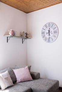a clock hanging on a wall above a couch at Casa Angiolina - Holidays - Appartamento Dolce Letargo in Morcote