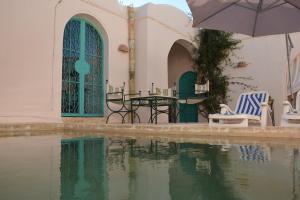 a patio with a table and chairs and an umbrella at Dar Lily in Erriadh