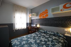 a bedroom with a bed and a desk and a window at Hostal Gaudi Cuenca in Cuenca