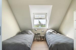 two beds in a room with a window at Boerderijwoning in Serooskerke