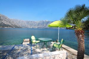 a table with chairs and an umbrella next to the water at Holiday Home Cattaro in Kotor