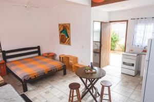a bedroom with a bed and a table and a kitchen at Villa Johen in Boicucanga