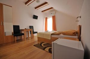 a bedroom with a bed and a desk and a tv at Guest House Korita in Grabovac