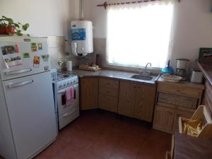 cocina con nevera blanca y fregadero en Departamentos Mitre en Luján