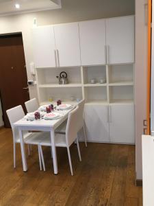 a white dining room table with white chairs and cabinets at Cooper Apartment in Genoa