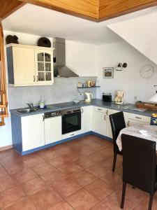 a kitchen with white cabinets and a sink and a table at "Bootsmannskammer" by Ferienhaus Strandgut in Born