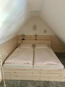 a bed in the eaves of a attic with white sheets at "Bootsmannskammer" by Ferienhaus Strandgut in Born