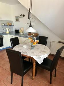 a dining room table with chairs and a vase of flowers on it at "Bootsmannskammer" by Ferienhaus Strandgut in Born +15 photos