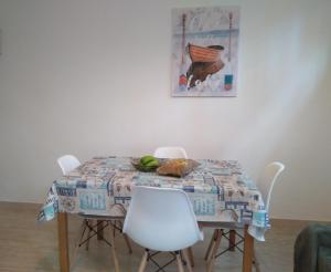 una mesa de comedor con sillas blancas y una pintura en Casa Tinko, en Las Palmas de Gran Canaria