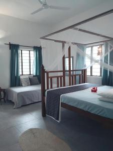 a bedroom with two beds with blue curtains at Barefoot Zanzibar in Michamvi