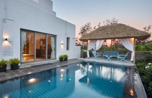 a swimming pool with two chairs and a umbrella at Manna Villa in Mahabalipuram