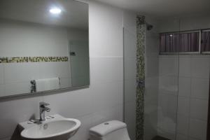 a bathroom with a sink and a toilet and a mirror at Hotel Monterrey in Barranquilla