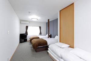 a hotel room with three beds and a window at Hummingbird Kanazawa in Kanazawa +40 photos