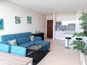 a living room with a blue couch and a kitchen at ABMAR- Por-do-sol, Vista mar, Remodelado, Wifi, 80mt Praia in Quarteira