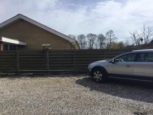 une voiture garée à côté d'une clôture devant une maison dans l'établissement Århus nord bed and breakfast, à Hinnerup