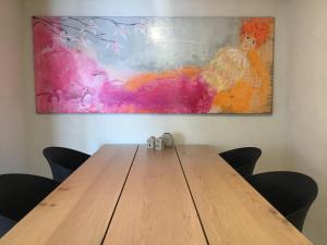 a wooden table with chairs in front of a painting at Århus nord bed and breakfast in Hinnerup