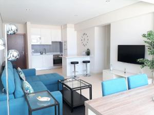 a living room with a blue couch and a kitchen at ABMAR- Por-do-sol, Vista mar, Remodelado, Wifi, 80mt Praia in Quarteira