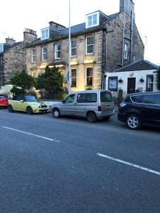 eine Gruppe von Autos, die an der Straßenseite geparkt sind in der Unterkunft Park View House in Edinburgh