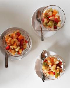 three bowls of fruit and vegetables on plates with spoons at Hotel Villa Principe in San Nicola Arcella