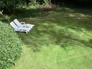 due sedie bianche sedute nell'erba in un cortile di Ferienwohnung Bachforelle a Neuenkirchen