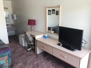 1 dormitorio con TV en un tocador con escritorio en Wheels Motel, en Greybull