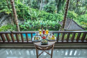 a table with a tray of food on a balcony at Alam Terrace Cottages in Ubud