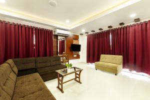 a living room with red curtains and a couch and a chair at Burooj Hotel in Cochin