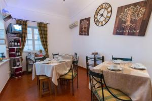 a dining room with two tables and a clock on the wall at Hospedaria Os Condes in Reguengos de Monsaraz