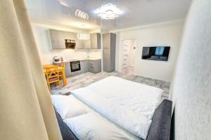 a white room with a bed and a kitchen at Apartment Voskresenska 18 , Парковые Озера in Kyiv