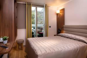 une chambre avec un lit, un bureau et une fenêtre dans l'établissement Hôtel de la Tour Eiffel, à Paris