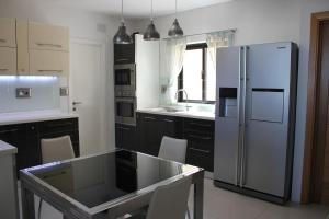 a kitchen with a refrigerator and a table with chairs at Sunny Lodge Apartment in St Paul's Bay