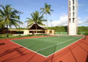 a tennis court in front of a building with palm trees at Nannai Beira Mar Porto de Galinhas 307 in Porto De Galinhas