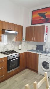 a kitchen with a stove and a sink and a dishwasher at The Tramway House in Carrickfergus