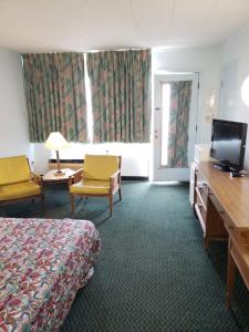 a hotel room with a bed and two chairs and a television at Budget Inn Horseheads in Horseheads