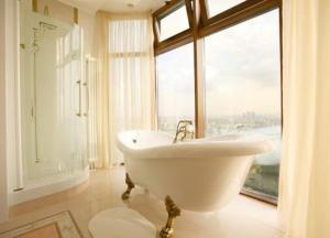 ein Bad mit einer Badewanne und einem großen Fenster in der Unterkunft Triumph Palace Boutique Hotel in Moskau