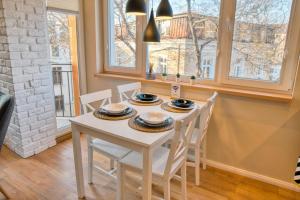 a white table and chairs in a kitchen with windows at Apartment Audrey by SofiaSpot - central, metro to airport in Sofia
