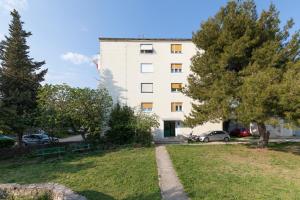 un edificio blanco alto con coches aparcados en un parque en Castropola Apartment, en Pula